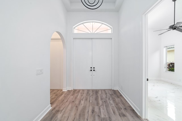 entrance foyer with light wood-type flooring, ceiling fan, and a towering ceiling