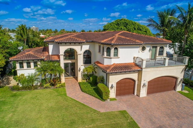 mediterranean / spanish-style house featuring a balcony, a tiled roof, decorative driveway, stucco siding, and a front lawn