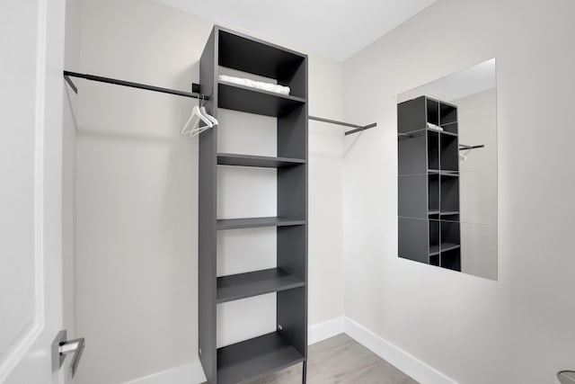 walk in closet with light hardwood / wood-style floors