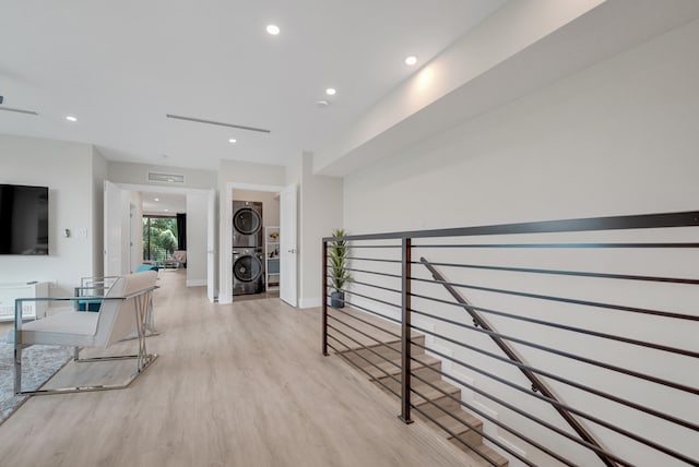 hallway featuring light hardwood / wood-style flooring and stacked washing maching and dryer