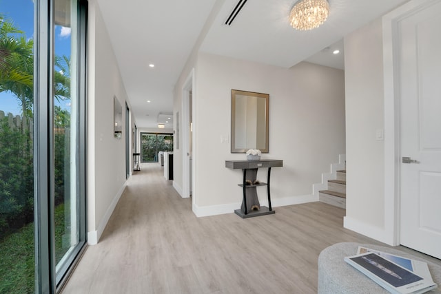 corridor with an inviting chandelier and light hardwood / wood-style flooring