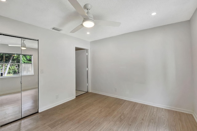 unfurnished bedroom featuring a closet, ceiling fan, a textured ceiling, and light hardwood / wood-style floors