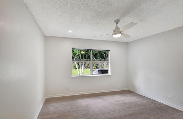 spare room with a textured ceiling, light wood-type flooring, and ceiling fan