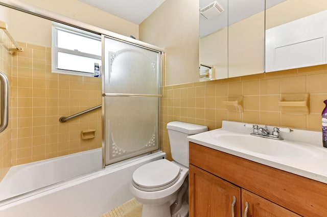 full bathroom with vanity, shower / bath combination with glass door, toilet, tile walls, and tasteful backsplash