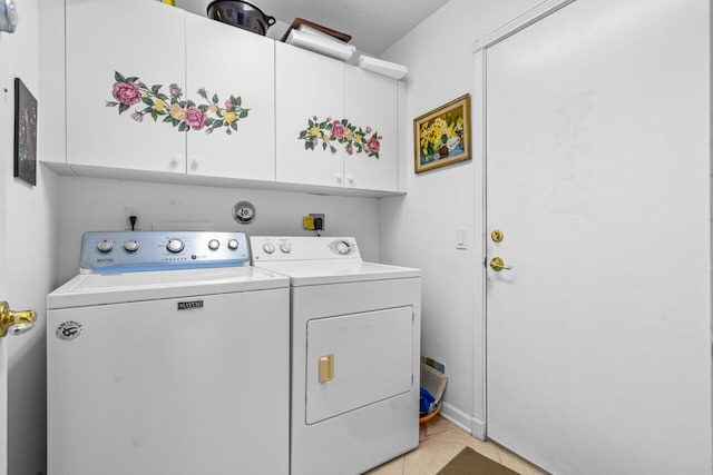 washroom with light tile patterned floors, cabinets, and washer and dryer