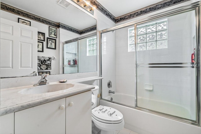 full bathroom with combined bath / shower with glass door, vanity, toilet, and a healthy amount of sunlight