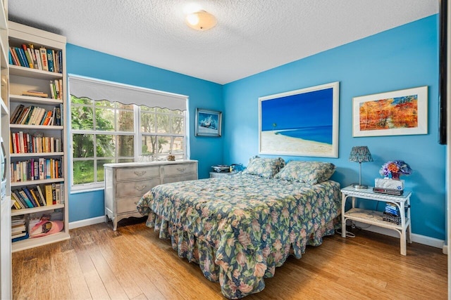 bedroom with a textured ceiling and light hardwood / wood-style floors