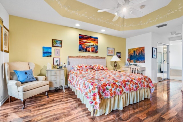 bedroom featuring dark hardwood / wood-style flooring, ensuite bathroom, and ceiling fan