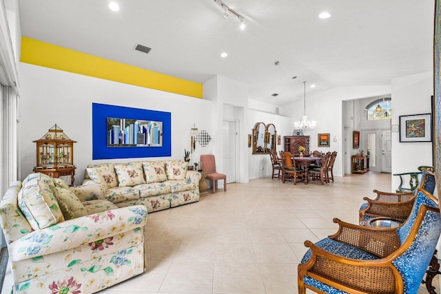 tiled living room featuring lofted ceiling, a chandelier, and track lighting