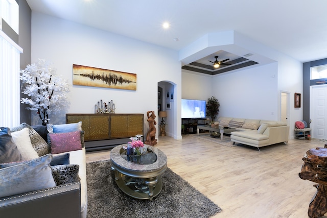 living room with a ceiling fan, a high ceiling, wood finished floors, and arched walkways