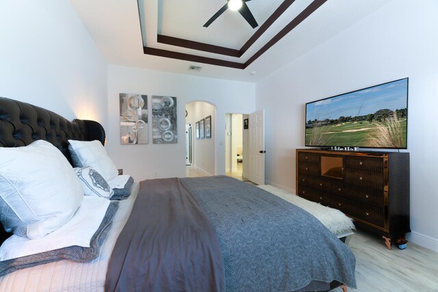 bedroom with visible vents, baseboards, a tray ceiling, arched walkways, and ceiling fan