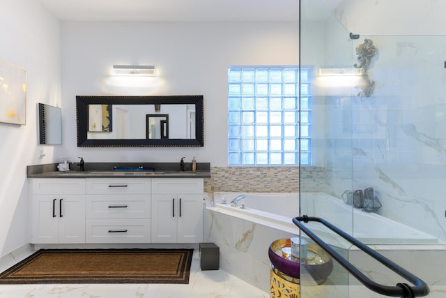 full bath with a sink, a tub with marble appearance, and double vanity