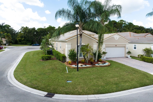 view of front facade with stucco siding, decorative driveway, a front yard, an attached garage, and a tiled roof