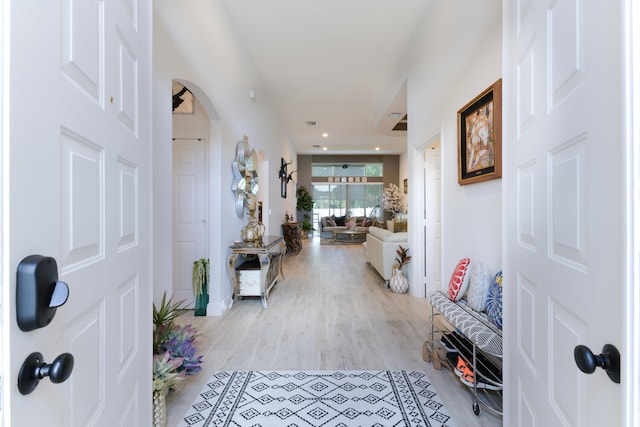 corridor featuring recessed lighting, arched walkways, and light wood finished floors