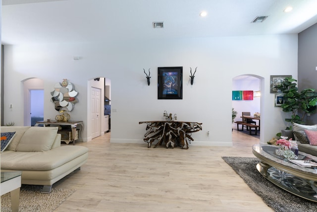 living room featuring recessed lighting, visible vents, arched walkways, and light wood finished floors