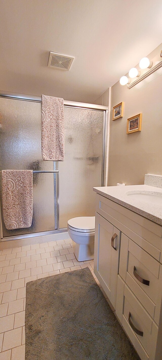 bathroom with toilet, vanity, visible vents, a shower stall, and tile patterned floors