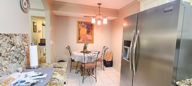 kitchen with stainless steel refrigerator with ice dispenser, light tile patterned floors, crown molding, hanging light fixtures, and white cabinets