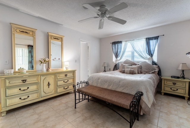 bedroom with ceiling fan, light tile patterned floors, and a textured ceiling