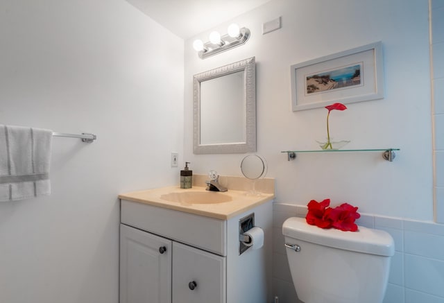 bathroom with vanity, toilet, and tile walls