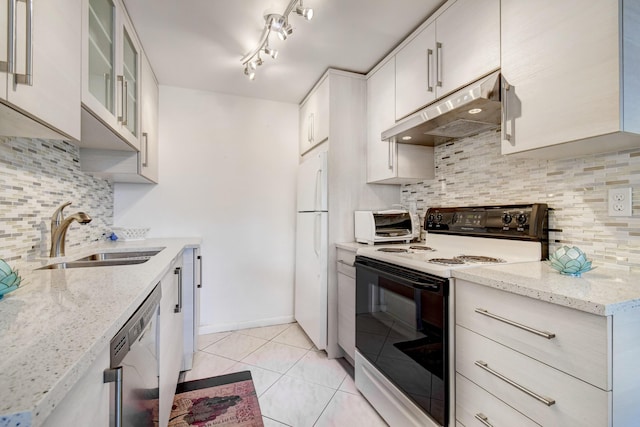 kitchen with light stone countertops, tasteful backsplash, white appliances, sink, and light tile patterned flooring