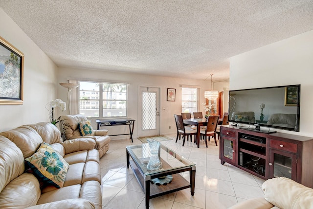 living room with a chandelier, a textured ceiling, a wealth of natural light, and light tile patterned flooring