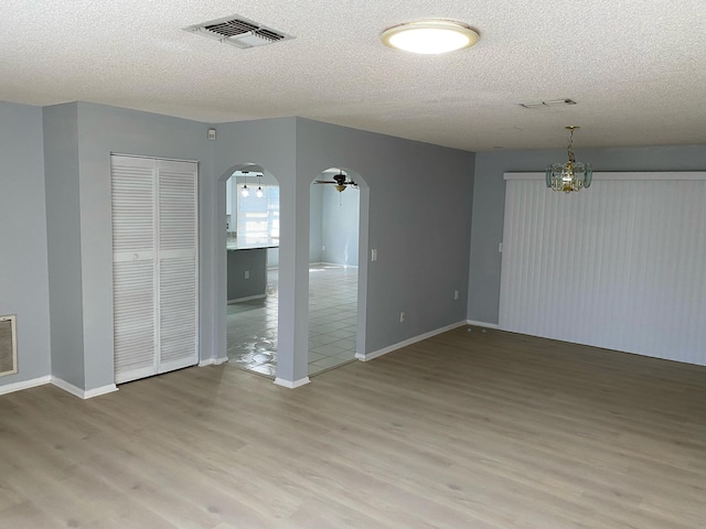 unfurnished room with a textured ceiling, light hardwood / wood-style floors, and ceiling fan