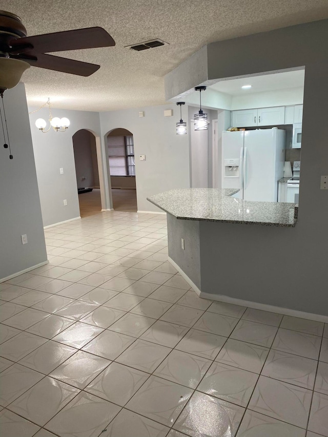 kitchen featuring a textured ceiling, white cabinets, white appliances, light stone countertops, and ceiling fan