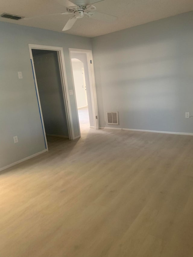 unfurnished bedroom featuring light wood-type flooring, ceiling fan, a walk in closet, and a closet