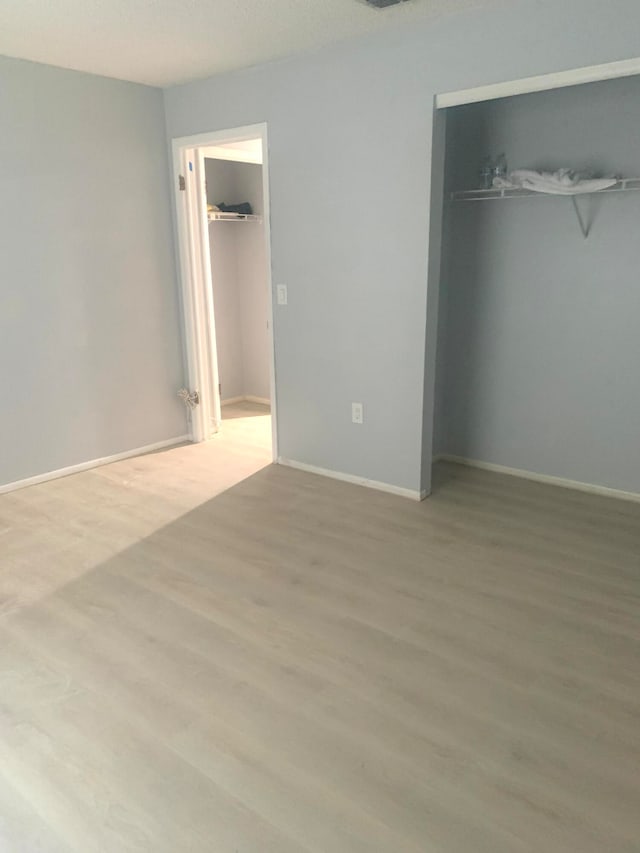 unfurnished bedroom with light hardwood / wood-style floors and a closet