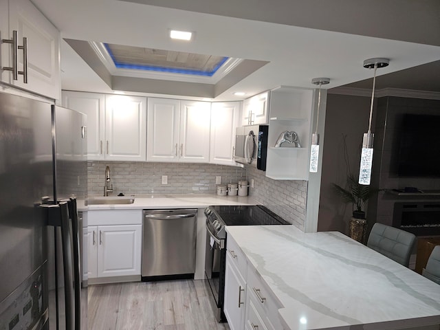 kitchen with white cabinetry, sink, stainless steel appliances, a raised ceiling, and light wood-type flooring