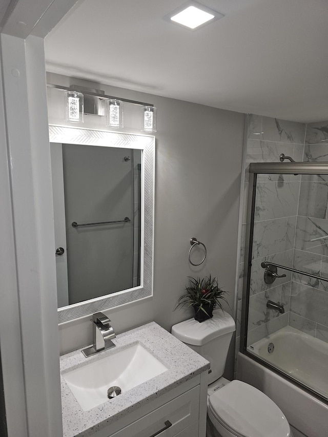 bathroom with toilet, bath / shower combo with glass door, and vanity