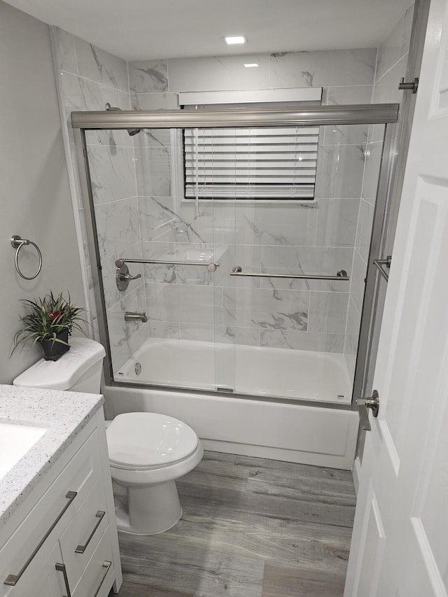 full bathroom featuring wood finished floors, vanity, toilet, and bath / shower combo with glass door