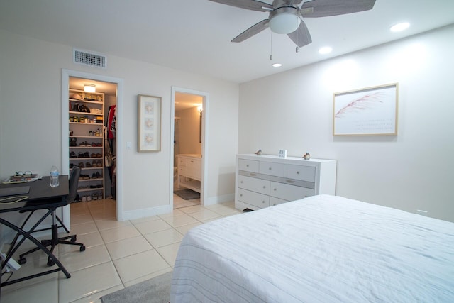 bedroom featuring a closet, light tile patterned flooring, a walk in closet, ensuite bathroom, and ceiling fan