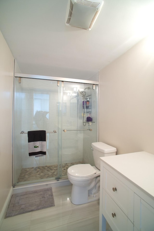 bathroom featuring vanity, a shower with shower door, and toilet