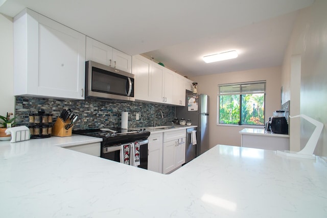 kitchen with sink, white cabinetry, stainless steel appliances, light stone countertops, and decorative backsplash