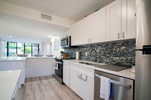 kitchen with white cabinets, backsplash, appliances with stainless steel finishes, and sink