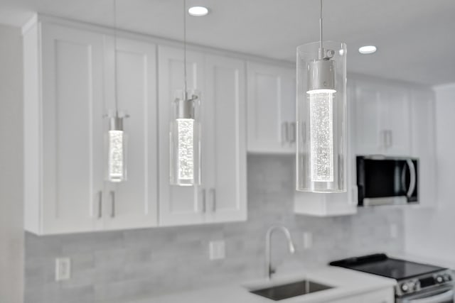 kitchen with stove, sink, tasteful backsplash, and white cabinetry