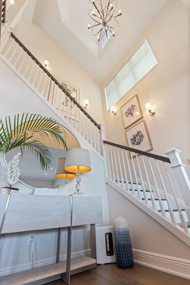 stairway with a chandelier, hardwood / wood-style floors, and a high ceiling