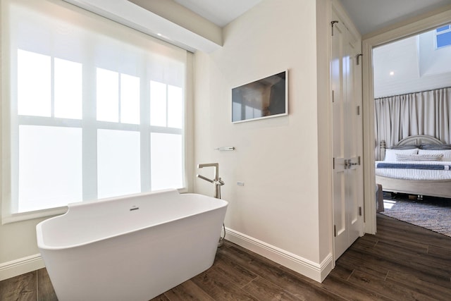 bathroom with a wealth of natural light, a bathing tub, and wood-type flooring