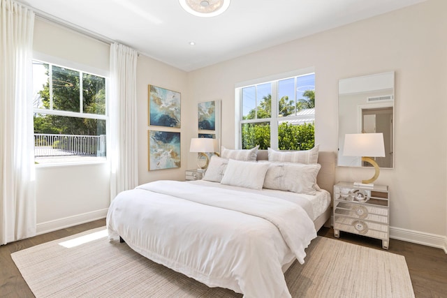 bedroom with multiple windows and dark hardwood / wood-style floors