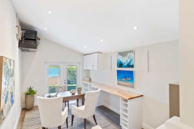 dining space with hardwood / wood-style floors, an AC wall unit, and vaulted ceiling