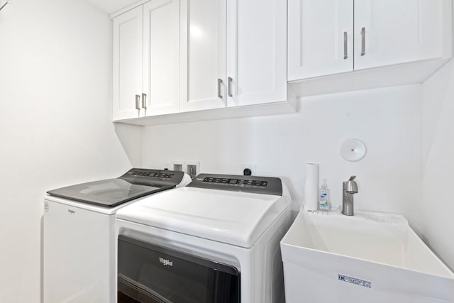 clothes washing area featuring independent washer and dryer, cabinets, and sink