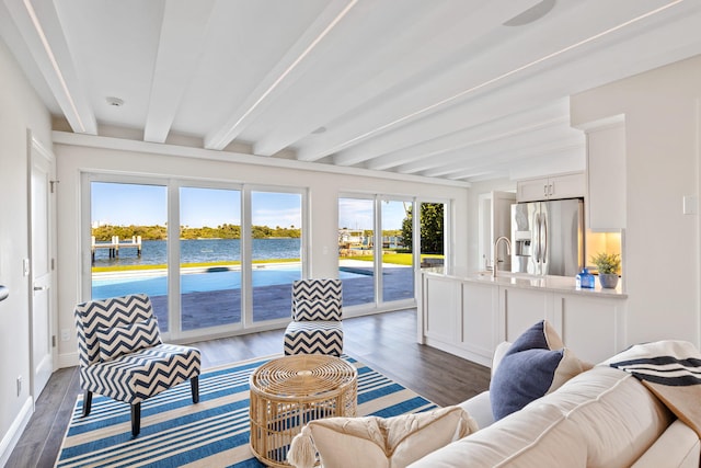 living room featuring dark wood-type flooring, sink, beamed ceiling, and a water view