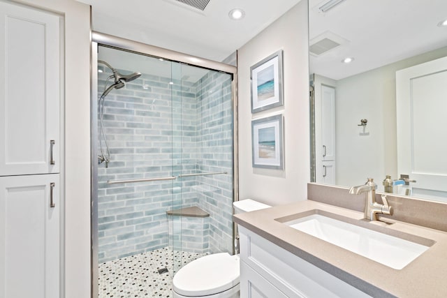 bathroom featuring a shower with shower door, toilet, and vanity