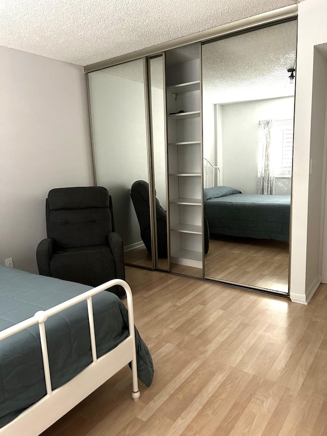 bedroom with a closet, a textured ceiling, and light hardwood / wood-style flooring