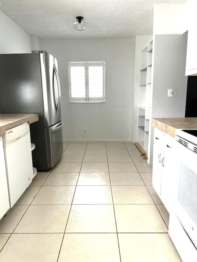 kitchen featuring white appliances, light tile patterned floors, white cabinets, and a textured ceiling