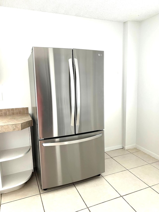 kitchen featuring a textured ceiling, stainless steel refrigerator, and light tile patterned floors