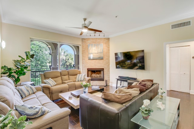 living room with crown molding, ceiling fan, dark hardwood / wood-style flooring, and a fireplace