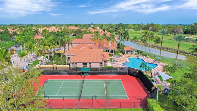 view of tennis court featuring a water view and a fenced in pool