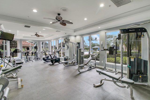 gym featuring a tray ceiling, ceiling fan, and ornamental molding